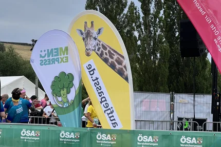 Firmenstaffel MD © buff.rocks GmbH Gelbe aufjepasst.de-Kampagnenflagge mit Giraffenmotiv an der Strecke der Magdeburger Firmenstaffel.