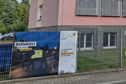 Altmarkkreis Salzwedel © Altmarkkreis Salzwedel Banner „Reflektier mal lieber“ am Zaun vor einem mehrstöckigen Schulgebäude im Altmarkkreis Salzwedel.