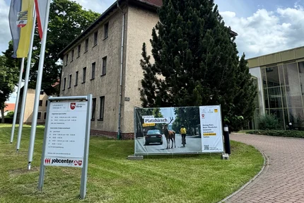 Landkreis Börde © Landkreis Börde - Landratsamt Oschersleben Fahnen, Kampagnenbanner „Sei mal ein Platzhirsch“ und Verwaltungsgebäude des Landkreises Börde in Oschersleben.