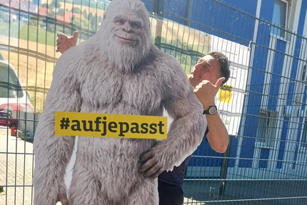 Bernburg © AGFK LSA Mann posiert mit aufjepasst-Kampagnenfigur in Bernburg vor Banner für Rücksicht und Verkehrssicherheit.