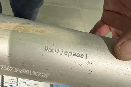 Gesundheitstag © AGFK LSA Nahaufnahme eines Metallrohrs mit eingraviertem Hashtag aufjepasst neben Informationsmaterial zur Radverkehrssicherheit.